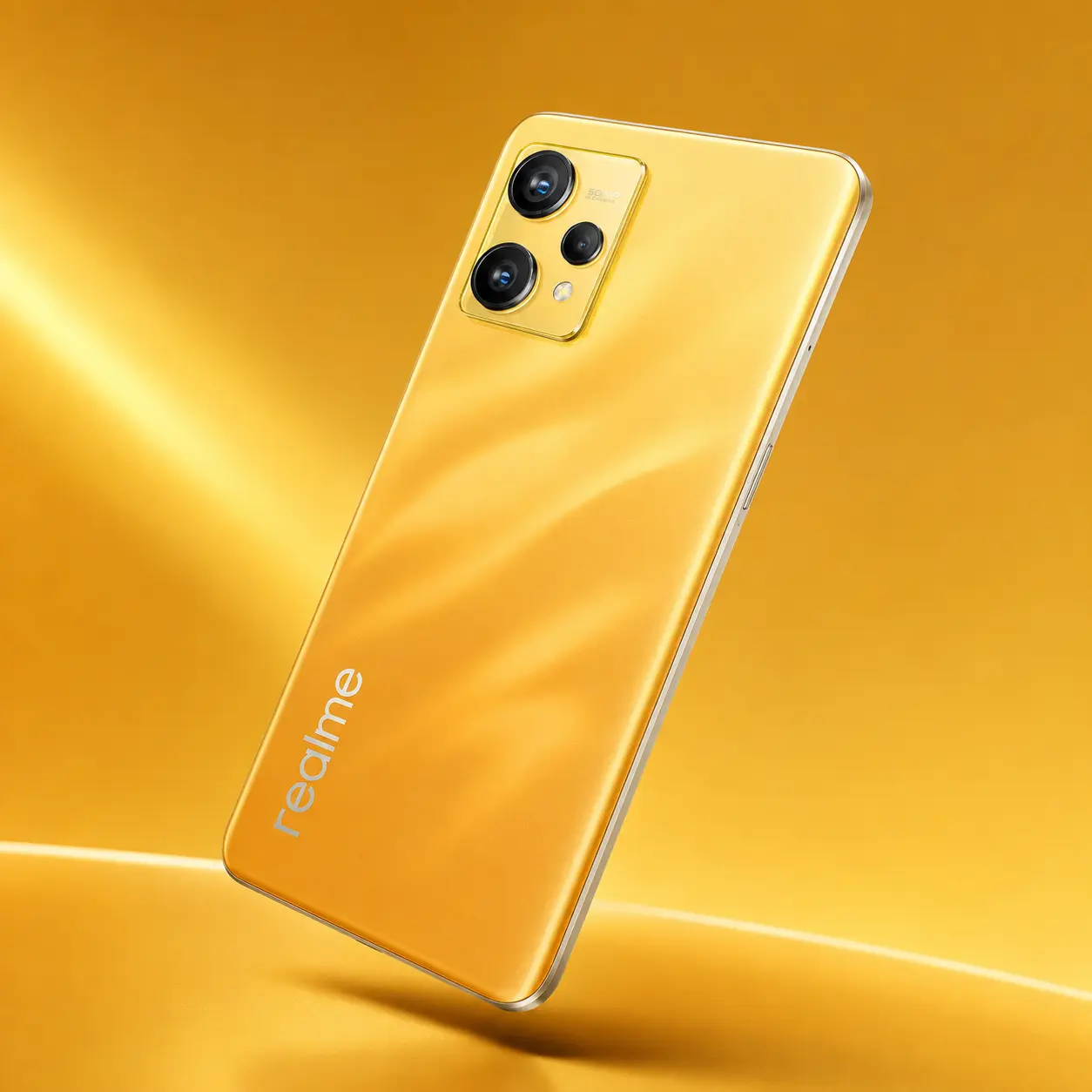 Teléfono Realme de color amarillo dorado con acabado brillante sobre una superficie satinada a juego